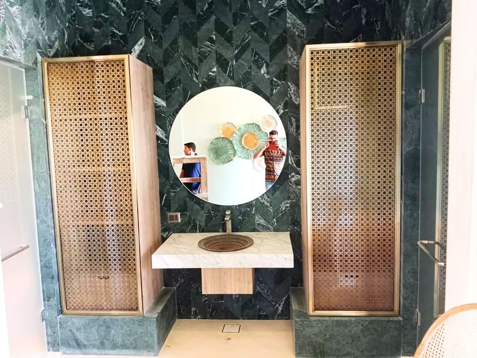 Spa washroom with green stone, timber screens and a brass basin