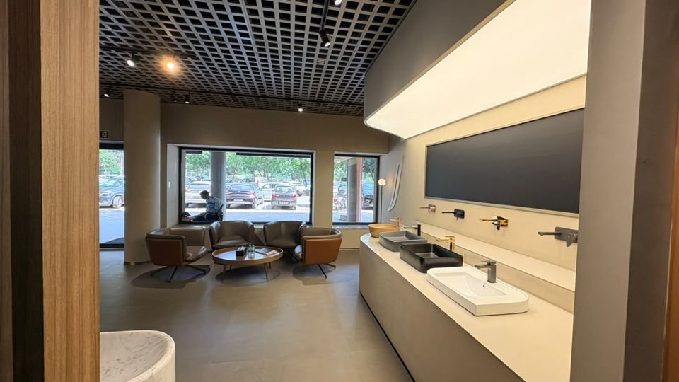 Window lounge & basin counter. Leather lounge chairs by the glazing, beside a long counter of basins with wall-mounted mixers.