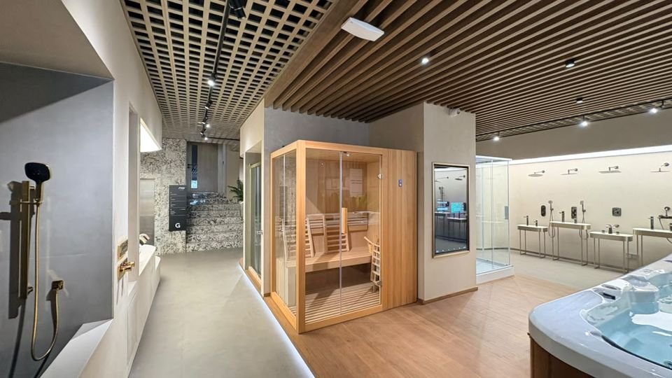 Sauna & shower wall. A timber sauna cabin, a mirrored display and a wall of shower fittings, with gold shower sets in the foreground.