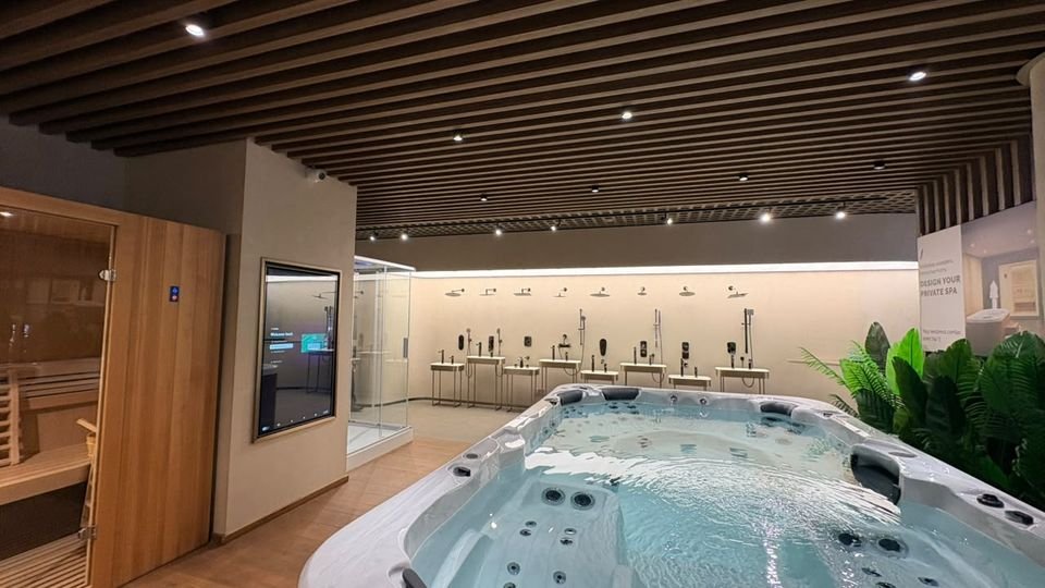 Spa pool & shower gallery. A spa pool, sauna cabin and continuous shower-display wall under warm timber slats.
