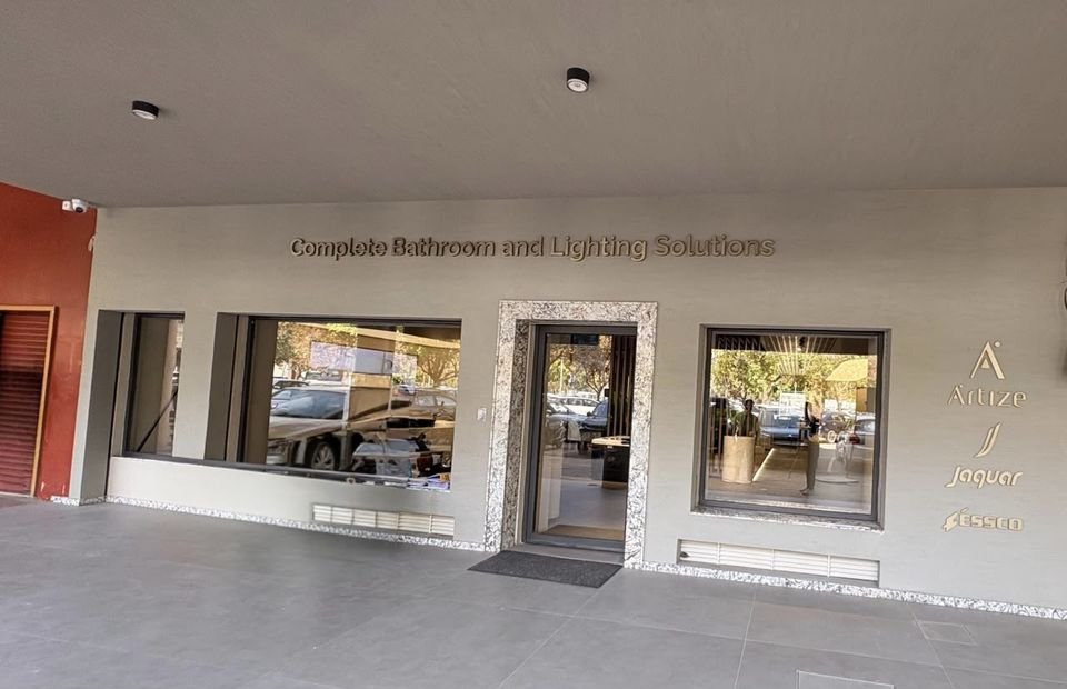 Street frontage. The entrance façade, with 'Complete Bathroom and Lighting Solutions' lettering and the Artize, Jaquar and Essco marks beside a stone-framed door.