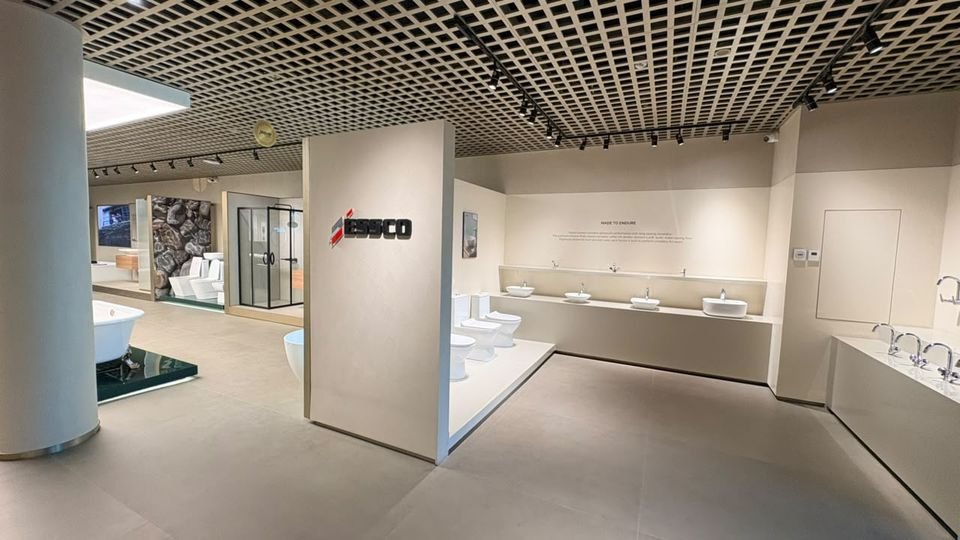 Essco basin & WC line-up. A long counter of basins and a row of WCs behind a branded Essco partition.