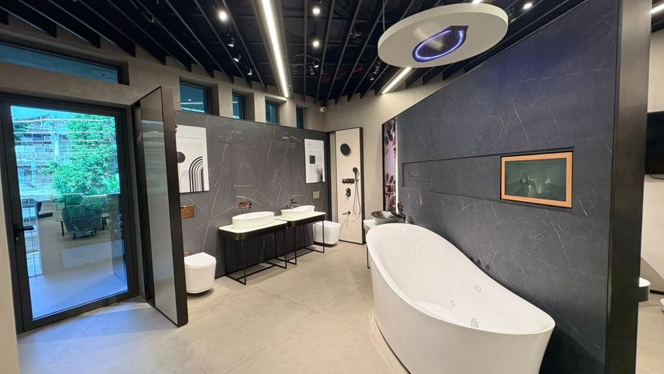 Freestanding bath & feature wall. A freestanding bath against a dark stone-effect wall, with basins on slim metal stands and a garden door.