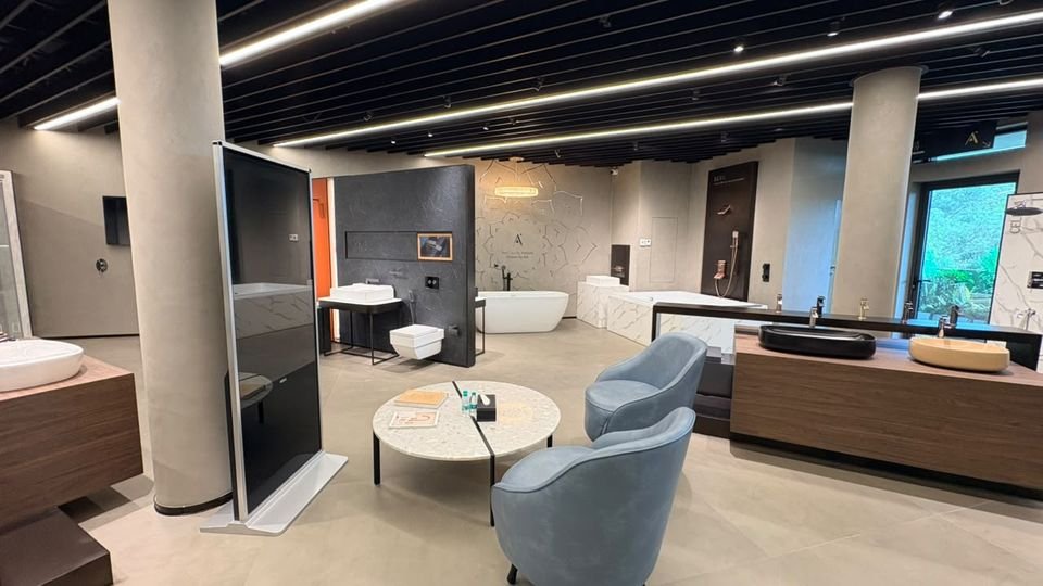 Gallery lounge. Lounge chairs and a terrazzo table among basin islands and bath settings.
