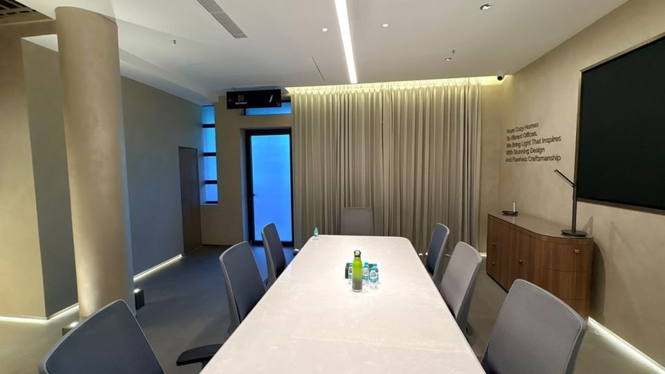 Boardroom. A long stone-top table beneath a linear light, with a wall graphic about light and craftsmanship.