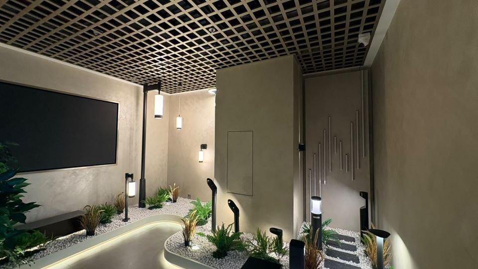 Landscape lighting garden. Bollards, spike lights and wall lights in a planted pebble bed with a lit, curving edge.