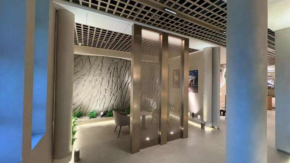 Perforated screen & textured wall. Perforated metal screen panels before a sculpted wall, lit from below.