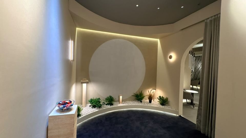 Moon alcove. A circular backlit disc in a curved alcove, with wall lights and a planted bed on dark carpet.