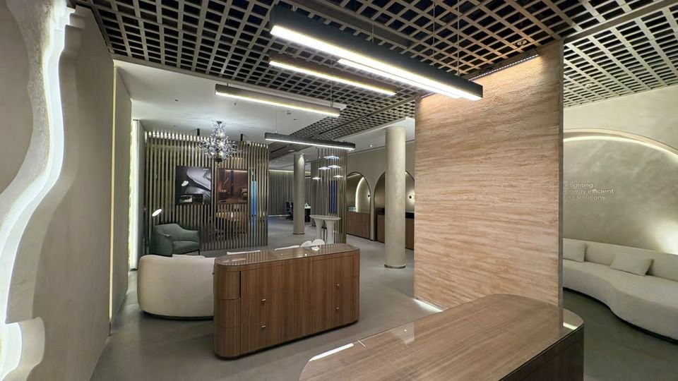 Reception counter & lounge. A timber counter, linear pendants and a stone-look column leading to lounge seating.